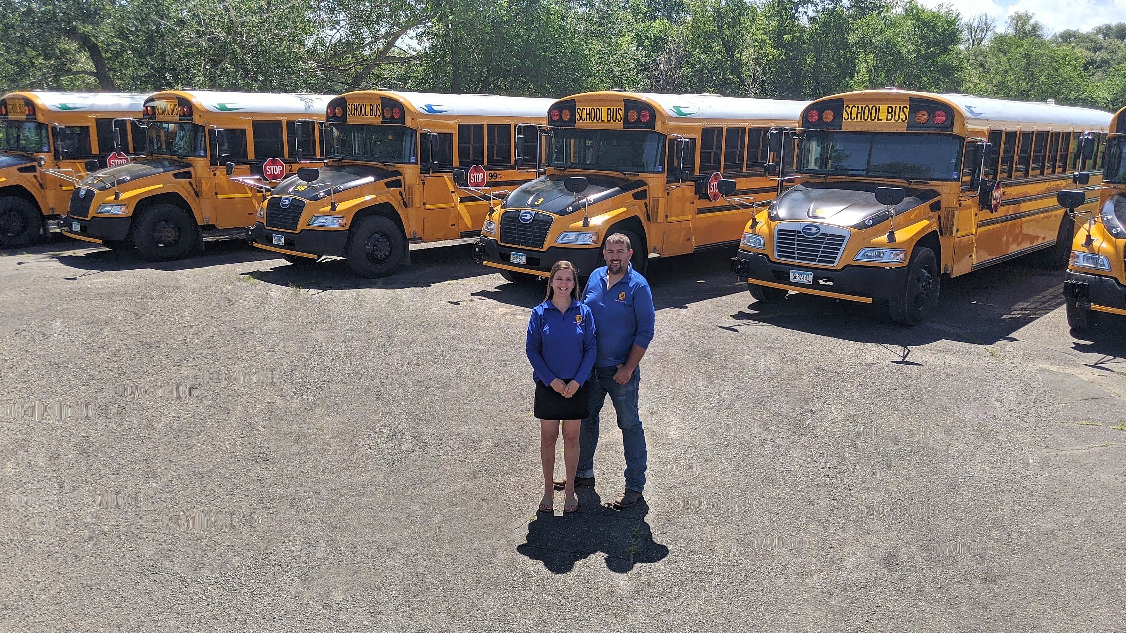 Mike and Jenny Aksmit with their three kids and family dog posing for a photo next to one of their school buses