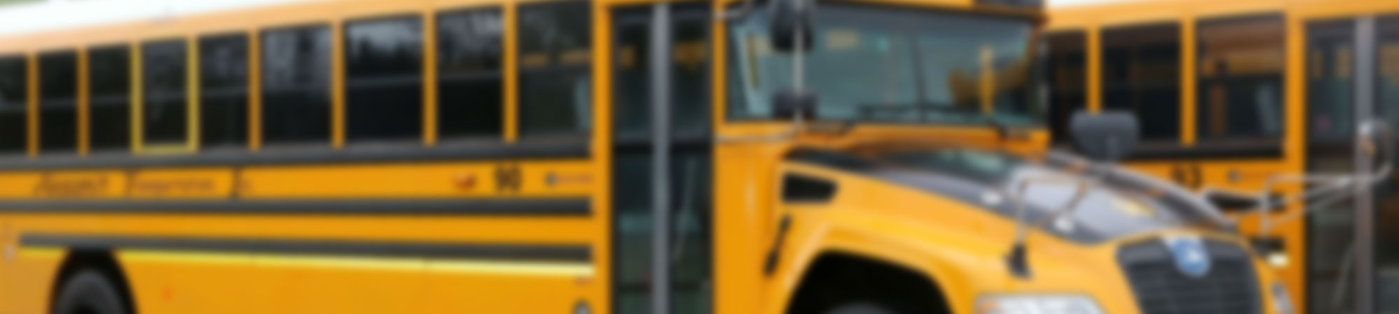Blurred photo of a school bus in the background with the words Drivers Wanted circled in the foreground