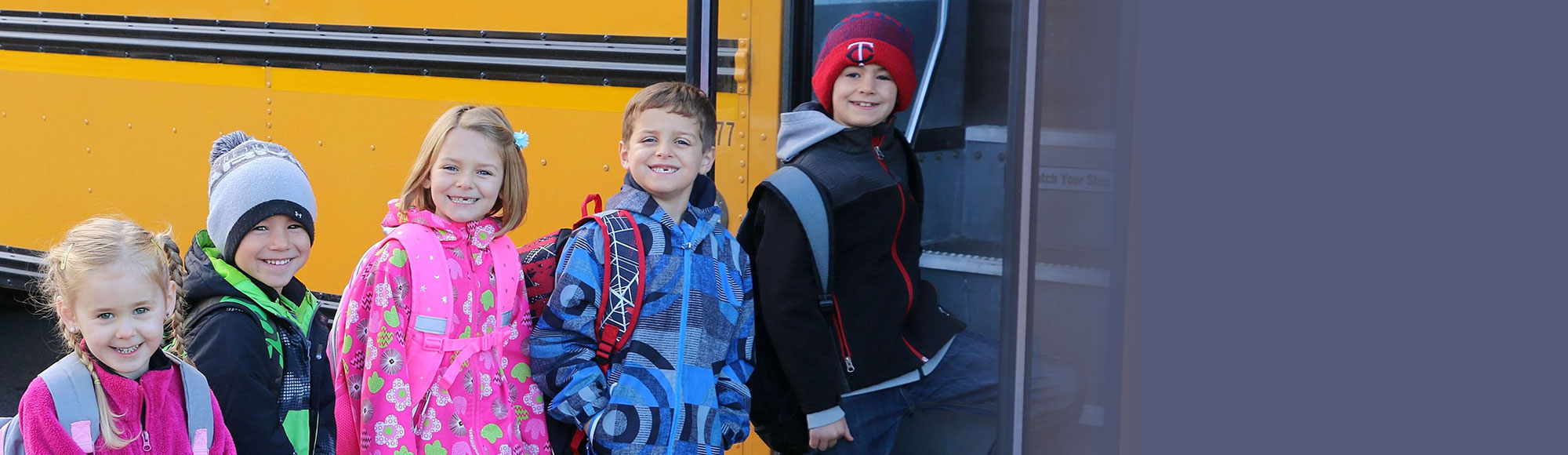 Group of kids getting on the school bus from the bus stop